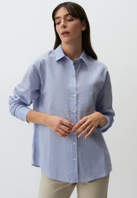 Blauw-wit gestreept overhemd met knopen, lange mouwen, een kraag en een borstzak. De stof lijkt lichtgewicht en gestructureerd.