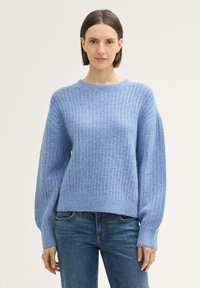 Heller blauer Strickpullover mit gerippter Textur, weiten Ärmeln und Rundhalsausschnitt, kombiniert mit Jeans. Einfache und entspannte Gestaltung.