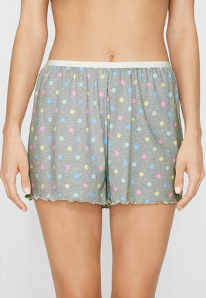 Grau melierte Pyjamashorts mit pastellfarbenen Punkten in Rosa, Blau, Gelb und Grün, getragen von einer Person, die mit entspannten Händen an den Seiten steht.
