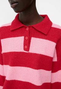 Red and pink striped knitted pullover with a collar, featuring four red buttons down the front and a soft texture.