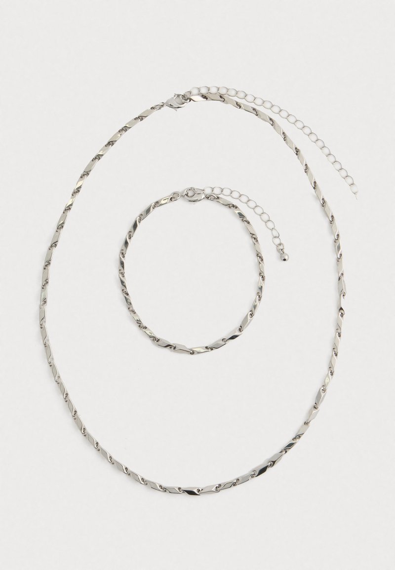 Silver twisted chain necklace and matching bracelet with adjustable clasps laid flat on white background.