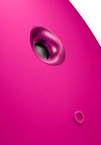 Enceinte rose avec une finition mate lisse, présentant une grille de haut-parleur circulaire proéminente et un petit accent circulaire sur le côté.