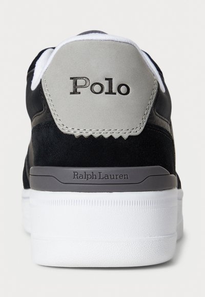 Sneaker en suède noir et textile avec une semelle en caoutchouc blanche, un accent de talon gris et un logo "Polo" à l'arrière. Design simple et moderne.