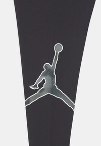 Tessuto nero con una grande silhouette bianca di una figura che salta con una palla da basket. Il design incorpora un motivo testurizzato a gradiente.