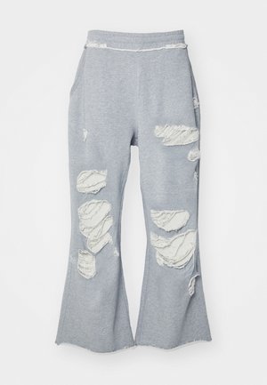 Lichtgrijze brede broek met meerdere grote gescheurde en rafelige gaten aan de voorkant en zijkanten, gemaakt van zachte stof.