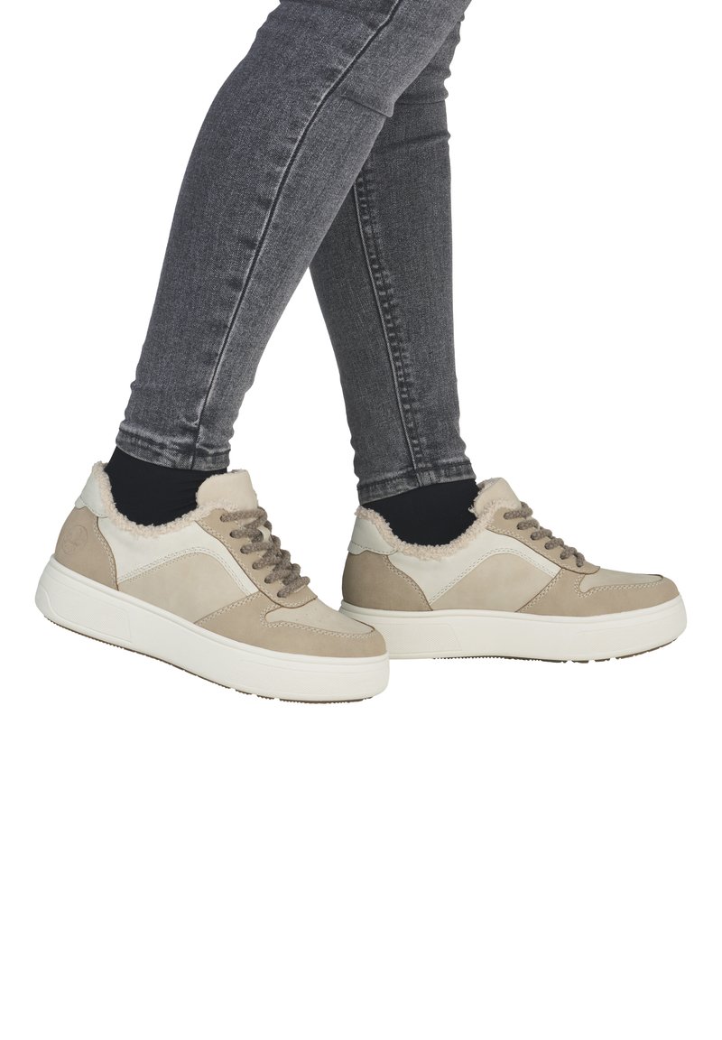 Baskets beiges avec un col doux et duveteux, présentant une texture en cuir lisse, des lacets gris et une semelle en caoutchouc blanc.