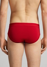 Boxer rouge pour homme en tissu lisse. Il présente une taille douce avec un logo et un ajustement serré, montrant l'arrière.