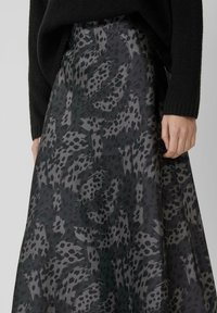 Maxi-jurk van een vloeiende stof met een grijs en zwart dierenpatroon. Soepele textuur met een hoge tailleband, gecombineerd met een zwarte gebreide top.
