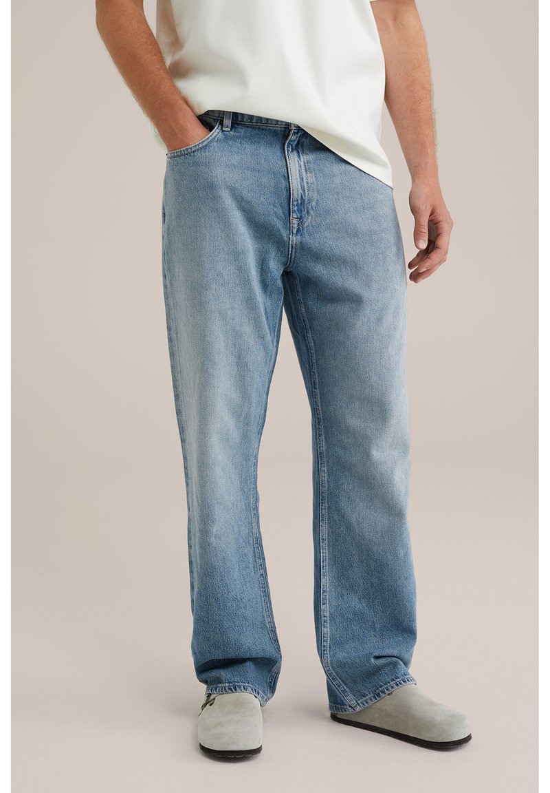 Lichtblauwe denim jeans met een relaxed fit, voorzien van een vijf-pocket ontwerp en subtiele vervaging. Draagt met een wit t-shirt en grijze klompen.