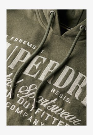 Zielona bluza z kapturem o fakturowanej tkaninie, z białym haftowanym napisem. Posiada sznurki z metalowymi srebrnymi końcówkami oraz luźny krój.