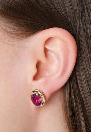 Close-up of ear with a gold stud earring featuring a large round deep pink gemstone.
