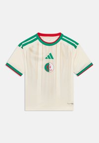 Μπλούζα ποδοσφαίρου Αλγερίας σε εκρού χρώμα με πράσινες και κόκκινες λεπτομέρειες, πράσινο λογότυπο Adidas, τρεις πράσινες ρίγες στους ώμους και έμβλημα της ομάδας στο στήθος.