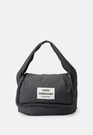 Sac à bandoulière noir matelassé avec une large sangle et une étiquette blanche indiquant "MADS NØRGAARD COPENHAGEN" sur le rabat avant.