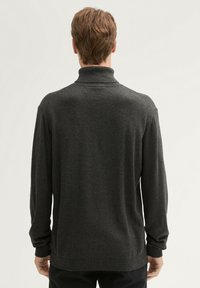 Ciemnoszary sweter z wysokim kołnierzem, długimi rękawami i luźnym krojem. Miękka tekstura i prążkowane detale przy mankietach i u dołu.