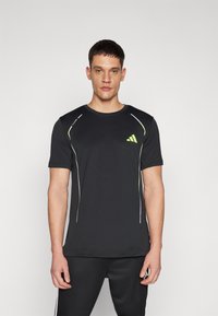 Sort atletisk t-shirt med korte ærmer, der har neongrønne og hvide accenter, rund halsudskæring og lille logo på brystet.
