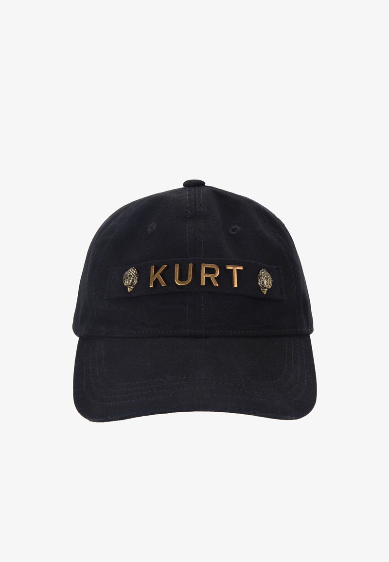 Casquette de baseball noire avec des lettres dorées formant le mot "KURT" et deux épingles décoratives dorées ressemblant à des coquillages ornés sur une bande en tissu.