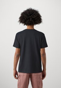 Black cotton t-shirt with a classic crew neckline, short sleeves, and a relaxed fit. No visible logos or patterns.