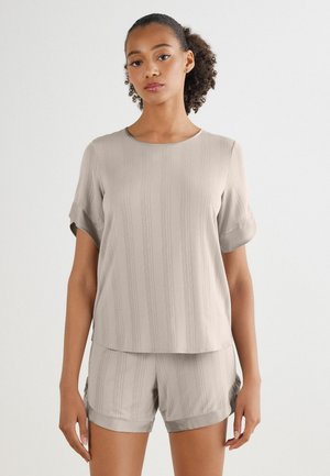 Ljust beige kortärmad topp med subtila vertikala ränder och rund halsringning, kombinerad med matchande shorts med vikta uppvik.