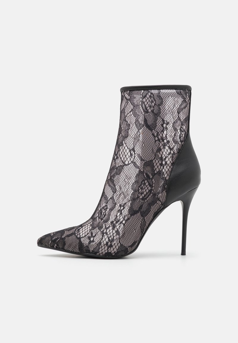 Bottine noire à talons hauts avec bout pointu et superposition de dentelle florale transparente couvrant la majeure partie de la chaussure.