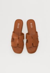 Brune sandle med utskåret design, med sydde detaljer. Glatt tekstur og flate såler. Merket "RAID" preget på toppen.