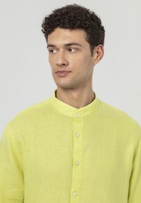 Linnen shirt in fel neon geel met een bandkraag en witte knopen, voorzien van een gestructureerde, lichte stof en een subtiele glans.