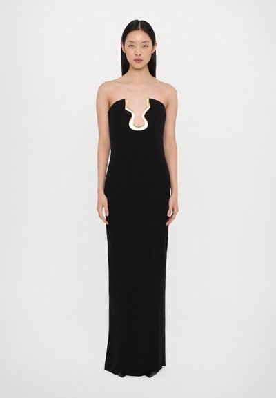 Robe maxi noire sans bretelles avec une silhouette ajustée, présentant un accent doré en forme de vague au niveau du décolleté. Tissu lisse et extensible.