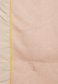 Texturerat tyg i en mjuk beige färg med en slät yta, kantad med en gul kant längs en av kanterna. Inga märkbara mönster eller beslag.