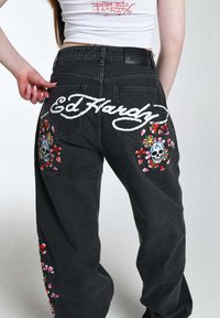 Jeans de mezclilla negra con el logo en blanco de "Ed Hardy" y bordado de calavera colorida con flores en los bolsillos traseros, diseño de ajuste holgado.