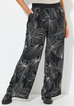 Zwarte wijde broek met een witte bloemenpatroon, voorzien van een elastische tailleband en zijzakken, gemaakt van een lichte stof.