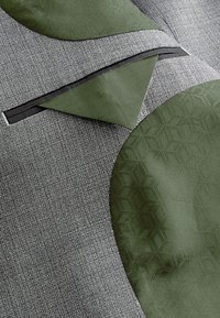 Tissu gris texturé avec un accent vert olive lisse, présentant des motifs géométriques et une bordure noire contrastante le long des bords.