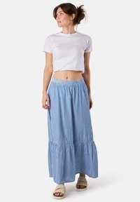 T-shirt court en coton blanc associé à une longue jupe maxi rayée bleue et blanche avec un ourlet en tiers et une taille élastique.