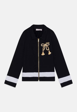 Schwarze Reißverschlussjacke mit Kragen, versehen mit weißen Streifen an Ärmeln und Saum. Gold bestickte Schleife mit Quasten auf der Vorderseite.