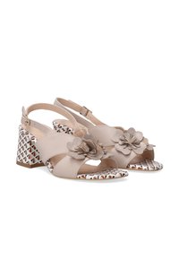 Beige leren slingback hakken met bloemaccenten, patroonblokhak en een geometrisch ontwerp op de binnenzool. Open teen stijl.