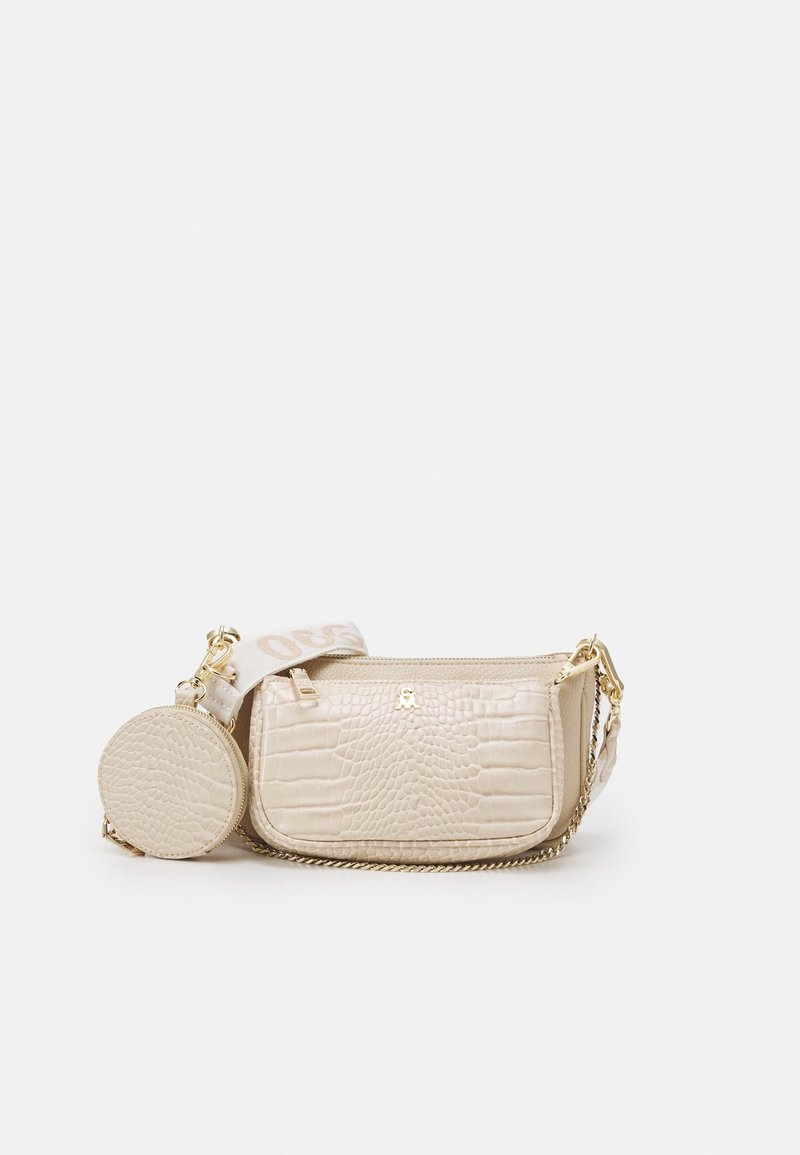 Borsa in pelle beige con effetto crocodile, dotata di un portamonete rotondo, hardware in oro e tracolla in tessuto con testo. Design compatto e strutturato.