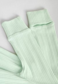 Világoszöld bordázott zoknik, puha tapintással és felhajtott mandzsettával, függőleges csíkokkal a részletek kiemelésére.