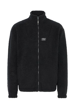 Chaqueta de forro polar negra con cuello alto, cremallera completa, exterior texturizado y un pequeño parche de logotipo en el pecho izquierdo. Diseño suave y cálido.