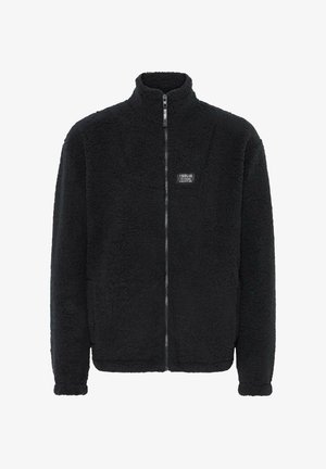 Fekete bolyhos dzseki magas gallérral, teljes cipzárral, textúrált külsővel és egy kis logóval a bal mellkasán. Puha, meleg kialakítás.