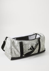 Bolso de viaje gris con un patrón geométrico, acentos negros y dos asas negras. Cuenta con un compartimento principal con cremallera y un forro interior.