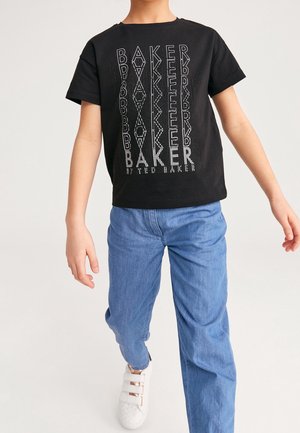 T-shirt noire avec le texte "BAKER" en blanc, dotée d'une impression texturée. Associée à un jean bleu et des baskets blanches avec trois fermetures à bande.