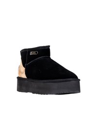 Botas de tobillo de ante negro con un panel lateral de corcho texturizado, suela de plataforma gruesa negra y un logotipo metálico decorativo en el tobillo.