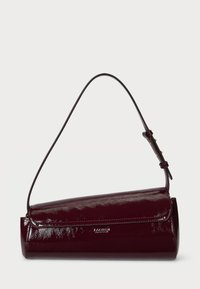 Fényes sötét burgundi henger alakú kézi táska állítható vállpánttal és fedélzárással egy sima háttér előtt.