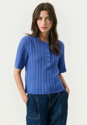 Maglione blu lavorato a maglia con maniche corte, scollo rotondo e chiusura a cinque bottoni. La texture è a coste con un sottile motivo a onde.