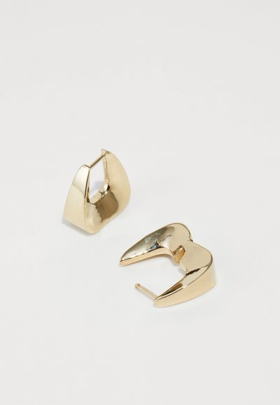Guld metal øreringe med et skulpturelt design featuring buede former og en åben udskæring. Glat tekstur, blank overflade og spidse accenter.