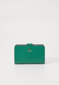 Grønn lærpung med teksturert overflate, gullbeslag med "FURLA" merkevare, og foldet lukking. Kompakt rektangulær form.