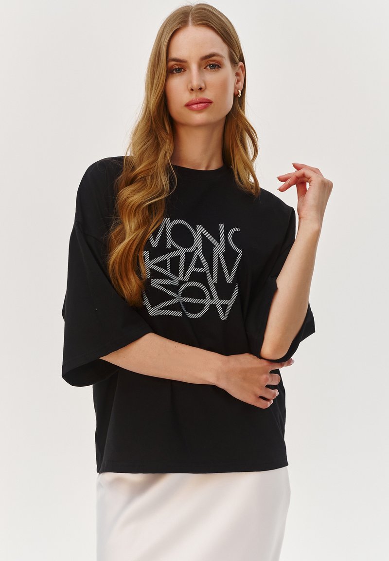 Czarna, oversize t-shirt wykonana z mieszanki bawełny, z srebrnym nadrukiem graficznym. Krótkie rękawy i luźny krój. Prosty, minimalistyczny design.
