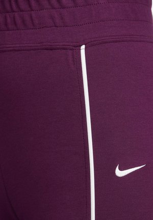 Lila Sporthose mit glatter Textur, mit einem weißen Seitenstreifen und einem kleinen weißen Nike-Logo am Unterschenkel.