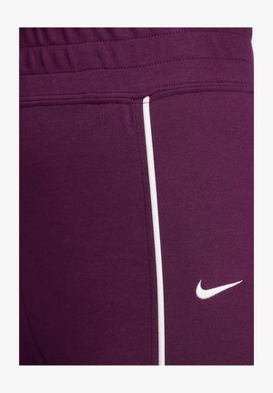 Lila Sporthose mit glatter Textur, mit einem weißen Seitenstreifen und einem kleinen weißen Nike-Logo am Unterschenkel.