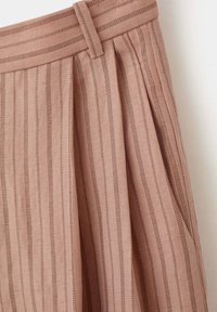 Jupe beige taille haute avec fines rayures verticales marron, passants de ceinture et plis sur un fond clair.