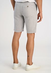 Grårandiga shorts med två bakfickor, knappdetaljer och rak skärning. Bärs med vita sneakers. Strukturerad lättviktsväv.