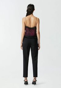 Svilena majica na bretele s leopard uzorkom u burgundiju i crnoj boji, s čipkastim rubom i crnim hlačama. Elegantnog kroja s delikatnim trakama.